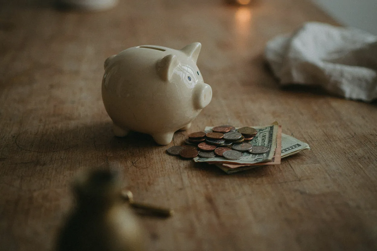 Piggy bank being filled with coins and bills representing emergency fund savings