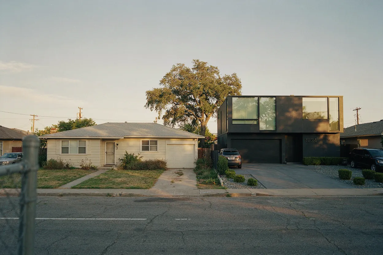 The houses didn't change. The math did. Two houses side by side — one modest from the 1970s, one modern and expensive — representing different economic eras